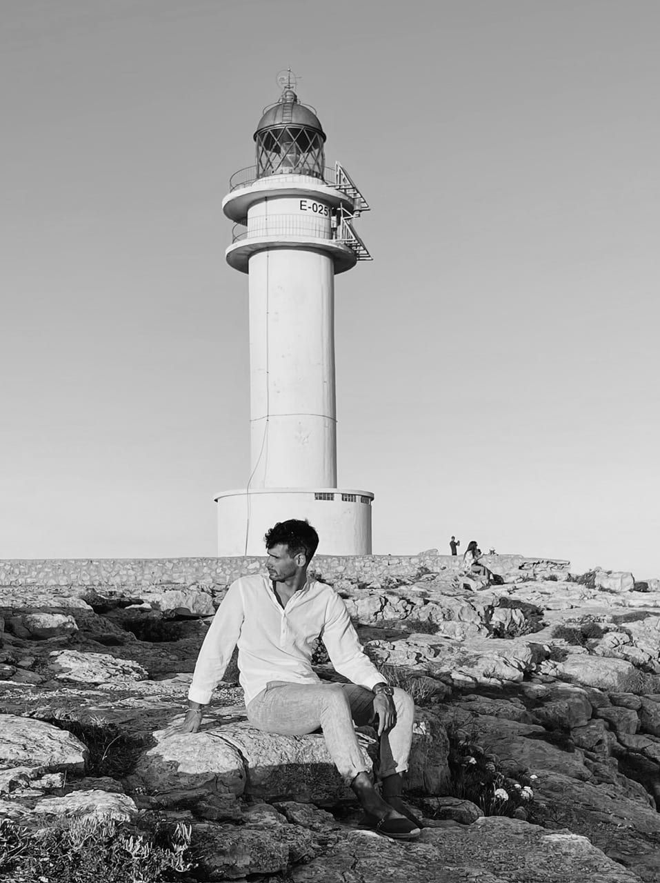 Bernat Montraveta Roca assegut a les roques davant d'un far